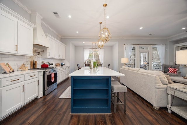 kitchen with stainless steel gas range, a kitchen island with sink, hanging light fixtures, a kitchen breakfast bar, and white cabinets