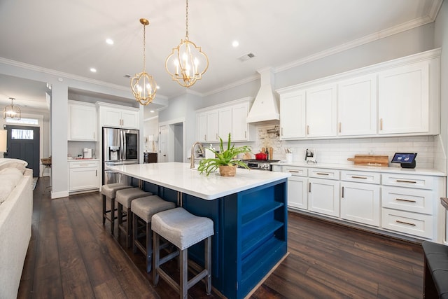 kitchen with custom exhaust hood, white cabinetry, and stainless steel fridge