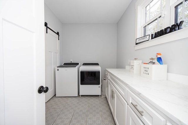 laundry room featuring cabinets, a barn door, and washing machine and dryer