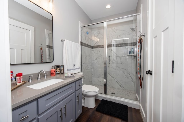 bathroom with vanity, hardwood / wood-style flooring, a shower with door, and toilet