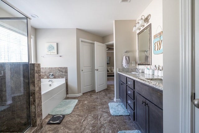 ensuite bathroom featuring baseboards, ensuite bathroom, a garden tub, vanity, and a shower stall