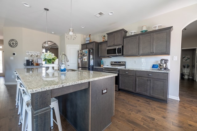 kitchen with visible vents, decorative backsplash, arched walkways, appliances with stainless steel finishes, and a sink