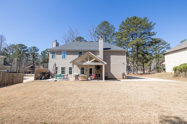 back of house featuring a ceiling fan, a patio area, fence, and a chimney