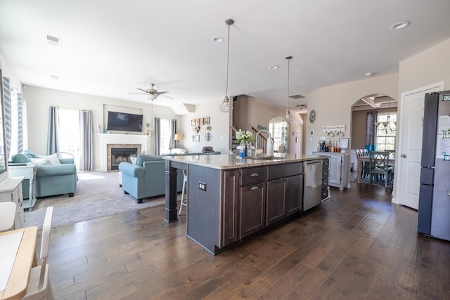 kitchen featuring dark brown cabinetry, visible vents, arched walkways, appliances with stainless steel finishes, and a sink