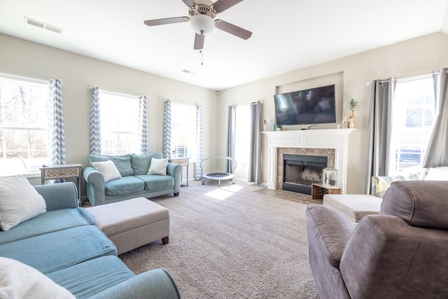 living room with visible vents, a fireplace, carpet flooring, and ceiling fan