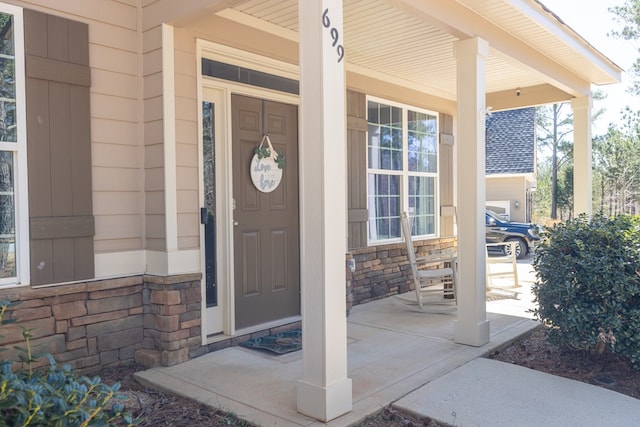 doorway to property featuring covered porch and stone siding