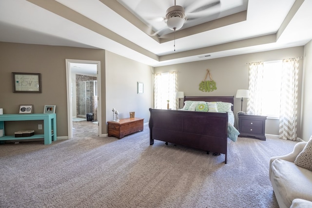 carpeted bedroom with connected bathroom, a ceiling fan, visible vents, baseboards, and a tray ceiling