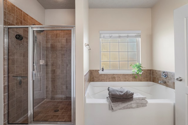 full bath with a bath, a shower stall, and a textured ceiling