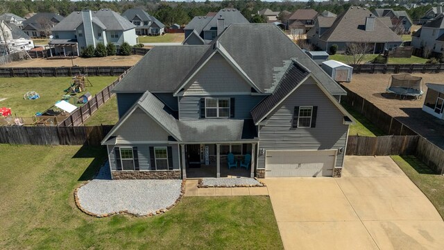 view of front of house featuring a front lawn, stone siding, a trampoline, a residential view, and a garage