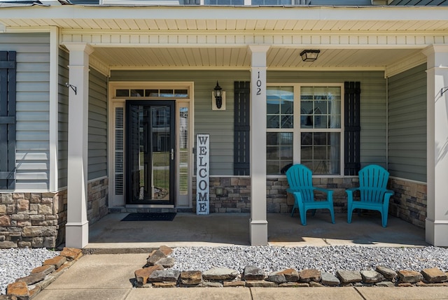 view of exterior entry featuring a porch and stone siding