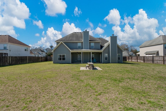 rear view of property featuring a patio, a fenced backyard, a lawn, and a chimney