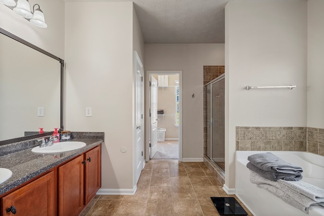 bathroom with a sink, a textured ceiling, a shower stall, double vanity, and a bath