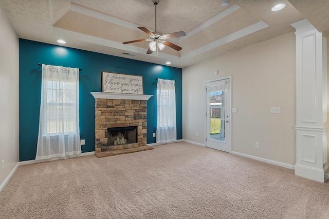 unfurnished living room featuring visible vents, a textured ceiling, a stone fireplace, carpet flooring, and a raised ceiling