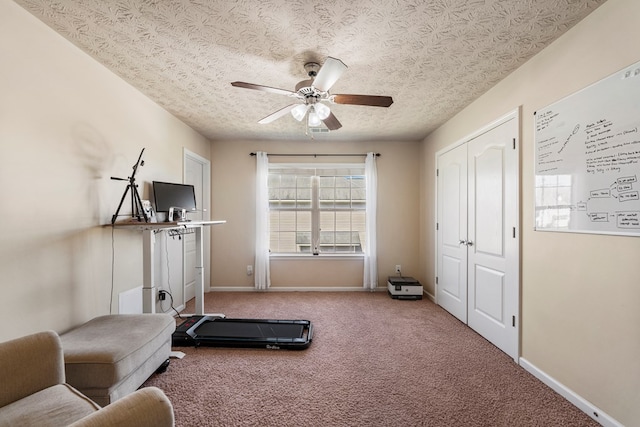 exercise area with a textured ceiling, baseboards, carpet, and a ceiling fan