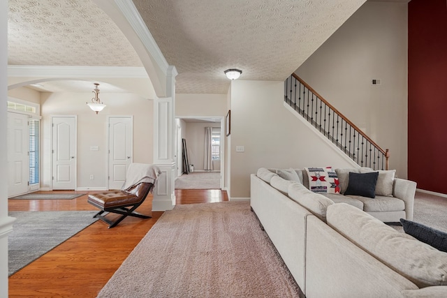 living area with stairway, wood finished floors, arched walkways, and baseboards