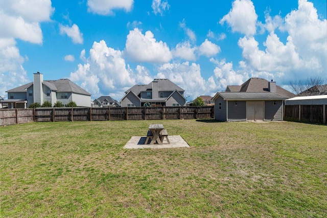 view of yard with an outbuilding, a fenced backyard, and a patio area