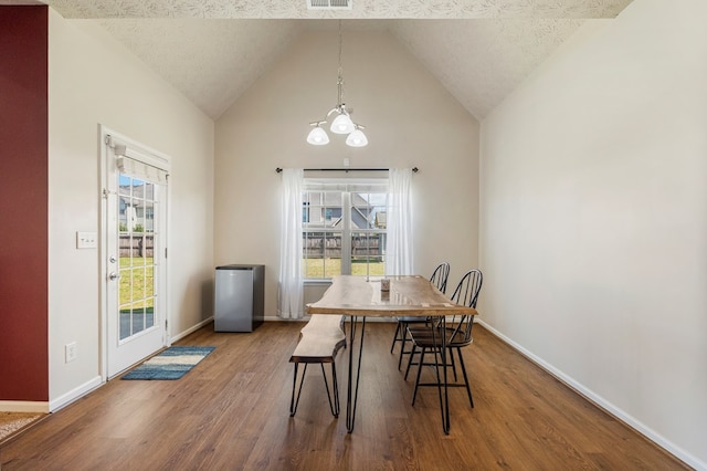 dining space with wood finished floors, baseboards, visible vents, vaulted ceiling, and a textured ceiling