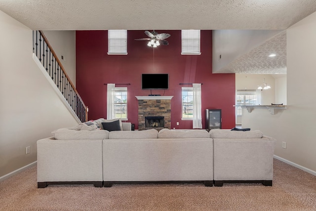 living area with light carpet, a stone fireplace, a high ceiling, and baseboards