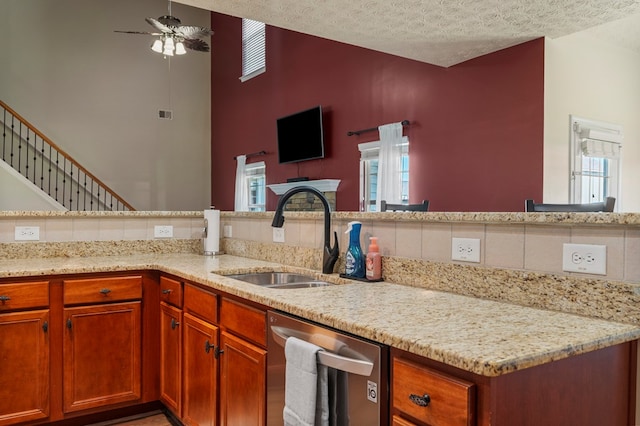 kitchen with a sink, light stone countertops, and dishwasher