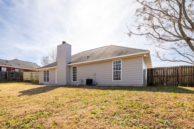 rear view of property featuring a yard and central air condition unit