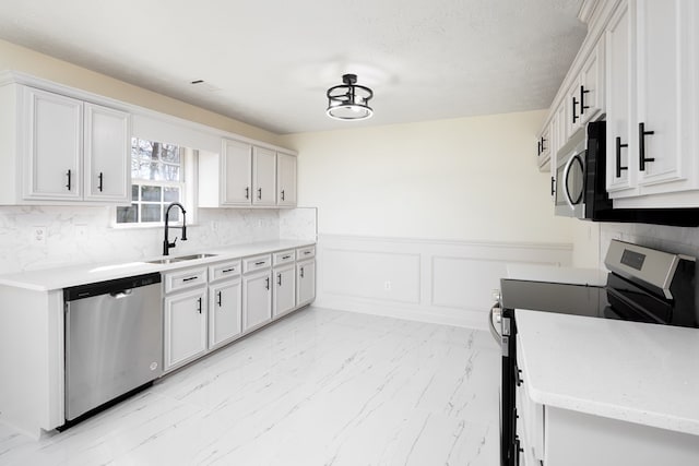 kitchen featuring sink, white cabinetry, a textured ceiling, stainless steel appliances, and decorative backsplash