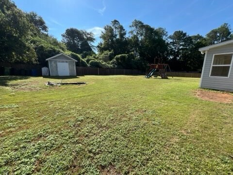 view of yard with a playground and a storage shed