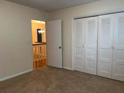 unfurnished bedroom with carpet, a textured ceiling, and a closet