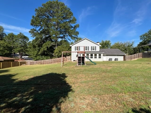 rear view of house featuring a playground and a yard