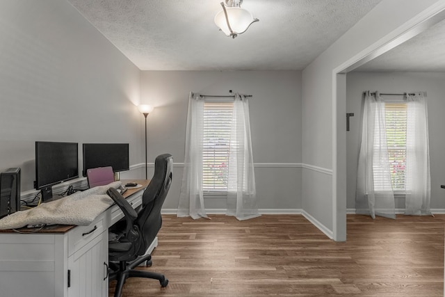 office space with a textured ceiling, baseboards, and wood finished floors