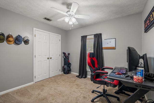 carpeted office space featuring visible vents, a ceiling fan, a textured ceiling, and baseboards