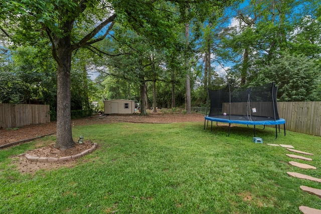 view of yard with an outdoor structure, a fenced backyard, a shed, and a trampoline