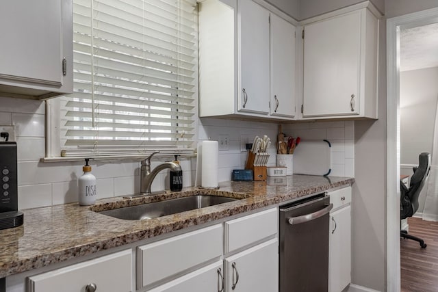 kitchen featuring white cabinets, light stone countertops, a sink, dishwasher, and decorative backsplash