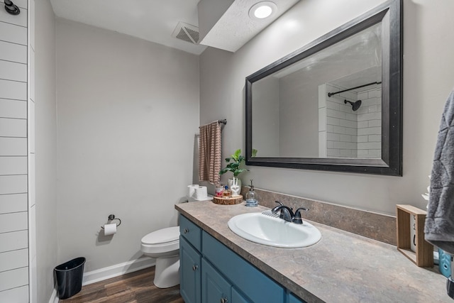 bathroom featuring visible vents, a shower, wood finished floors, vanity, and toilet