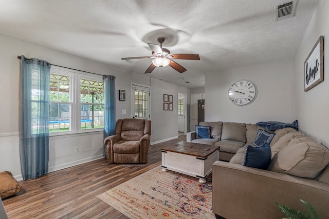 living area with visible vents, wood finished floors, baseboards, a textured ceiling, and a ceiling fan