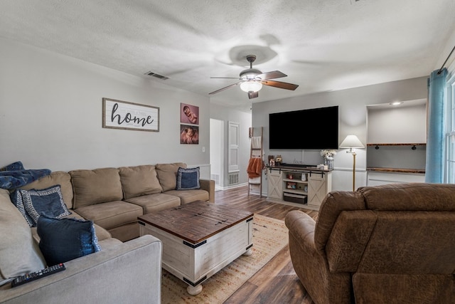 living area featuring a ceiling fan, wood finished floors, and visible vents