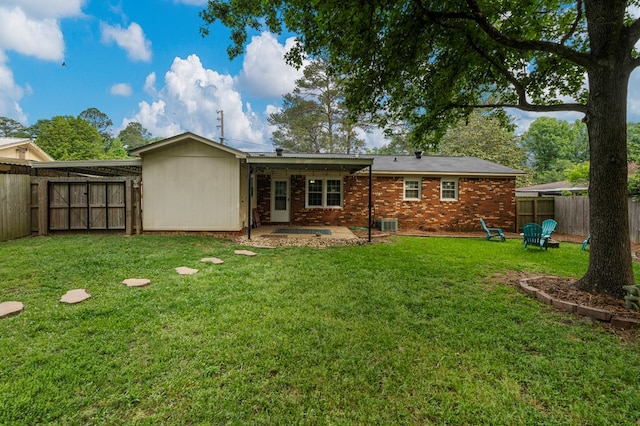 rear view of house with a patio, a fenced backyard, a lawn, and brick siding