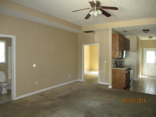1902 6th Ct, Phenix City, AL 36867 - kitchen with stainless steel range with electric stovetop, a ceiling fan, brown cabinetry, a textured ceiling, and light colored carpet