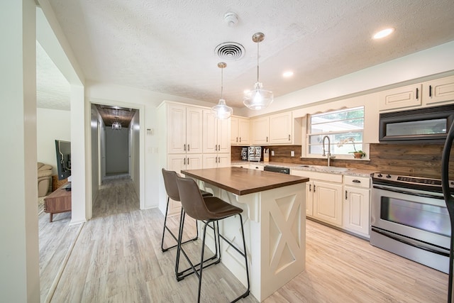 813 Crockett Dr, Columbus, GA 31904 - kitchen with black appliances, butcher block countertops, a textured ceiling, light wood-style floors, and a kitchen breakfast bar