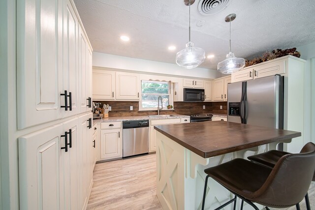 813 Crockett Dr, Columbus, GA 31904 - kitchen with dishwasher, black microwave, light wood-style flooring, backsplash, and a textured ceiling