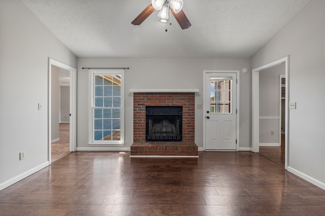 unfurnished living room featuring a textured ceiling, plenty of natural light, a ceiling fan, and a brick fireplace