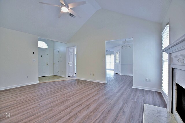84 Summerbrook Loop, Smiths Station, AL 36870 - unfurnished living room featuring high vaulted ceiling, ceiling fan with notable chandelier, baseboards, a fireplace with flush hearth, and visible vents