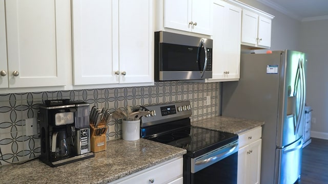 8840 Sullivans Dr, Midland, GA 31820 - kitchen with appliances with stainless steel finishes, crown molding, decorative backsplash, white cabinetry, and dark stone counters