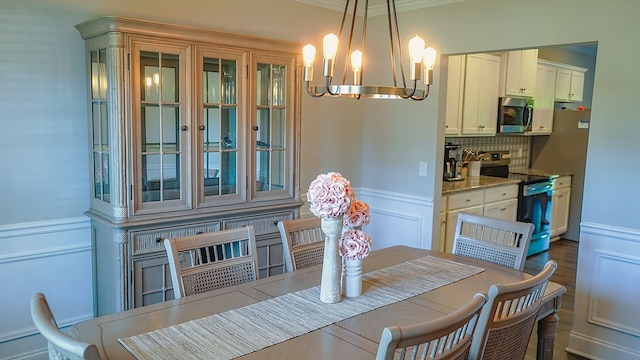 8840 Sullivans Dr, Midland, GA 31820 - dining space featuring a chandelier, a decorative wall, ornamental molding, and a wainscoted wall