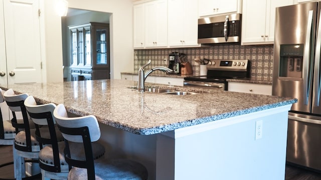 8840 Sullivans Dr, Midland, GA 31820 - kitchen featuring stainless steel appliances, a sink, light stone counters, white cabinets, and a breakfast bar