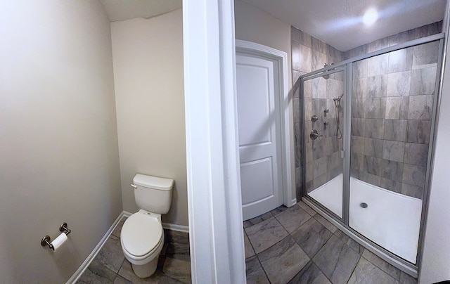 8840 Sullivans Dr, Midland, GA 31820 - bathroom with a shower stall, toilet, marble look tile flooring, and baseboards