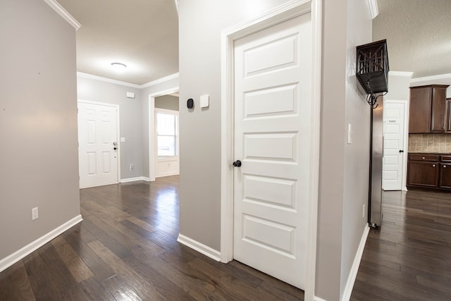 hall with ornamental molding, dark wood-type flooring, and a textured ceiling