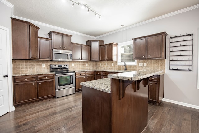 kitchen featuring crown molding, dark hardwood / wood-style floors, stainless steel appliances, and a kitchen breakfast bar