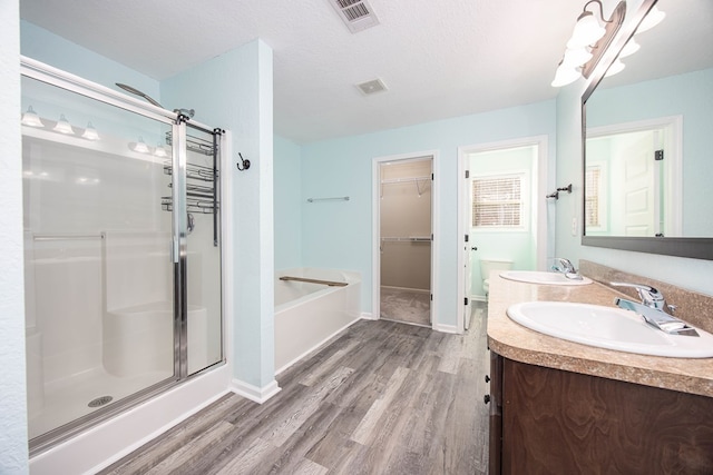 full bathroom featuring toilet, separate shower and tub, a textured ceiling, vanity, and hardwood / wood-style floors