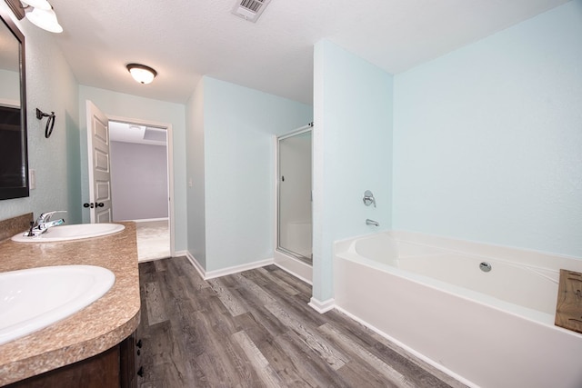 bathroom featuring vanity, hardwood / wood-style flooring, independent shower and bath, and a textured ceiling