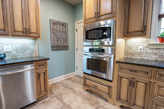 3450 Mckee Rd, Upatoi, GA 31829 - kitchen with appliances with stainless steel finishes, backsplash, dark stone countertops, baseboards, and brown cabinetry
